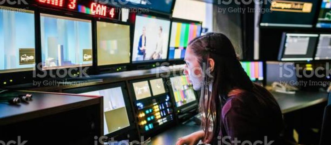 Студент університету дивиться на різні екрани під час використання обладнання телевізійної студії.
